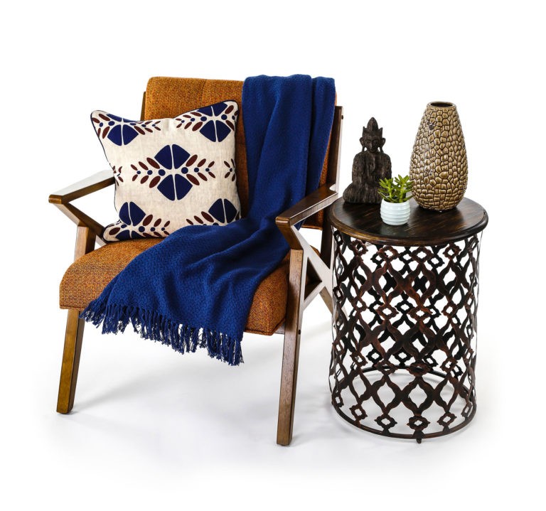 Wooden chair with a blue throw and cushion next to a small table with a decorative vase, statuette and succulent plant
