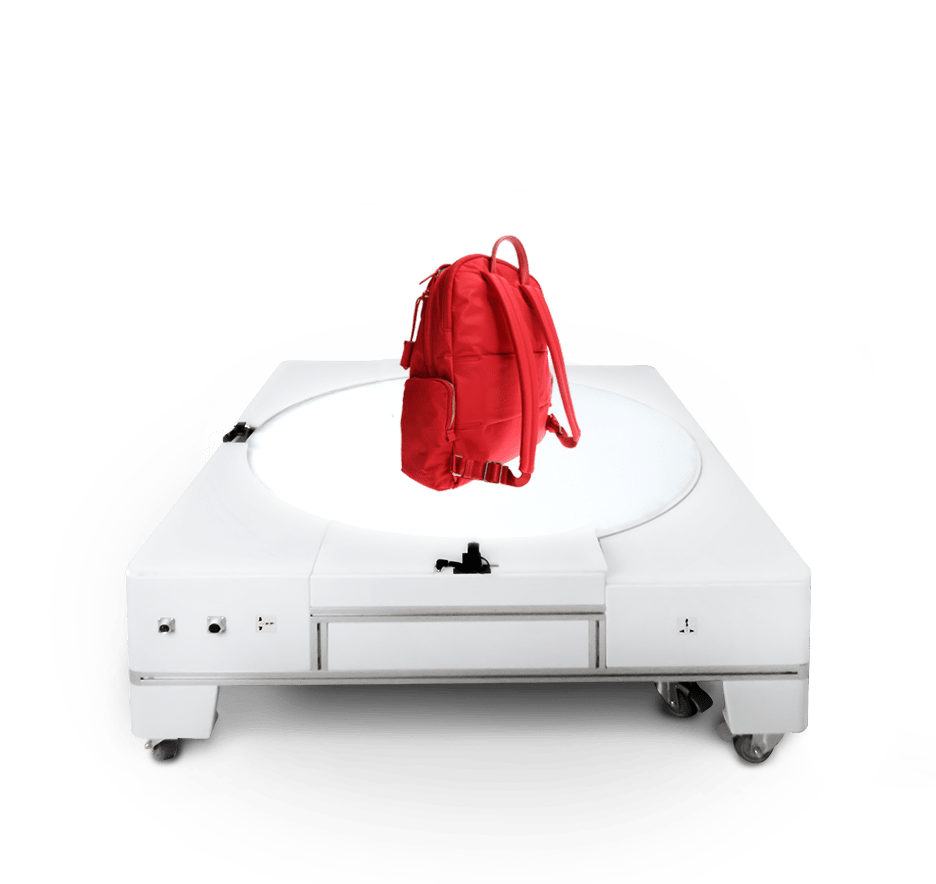 A red backpack sitting on an underlit turntable