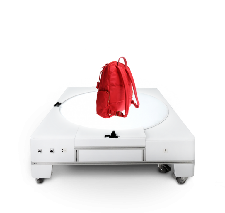 A red backpack sitting on an underlit turntable